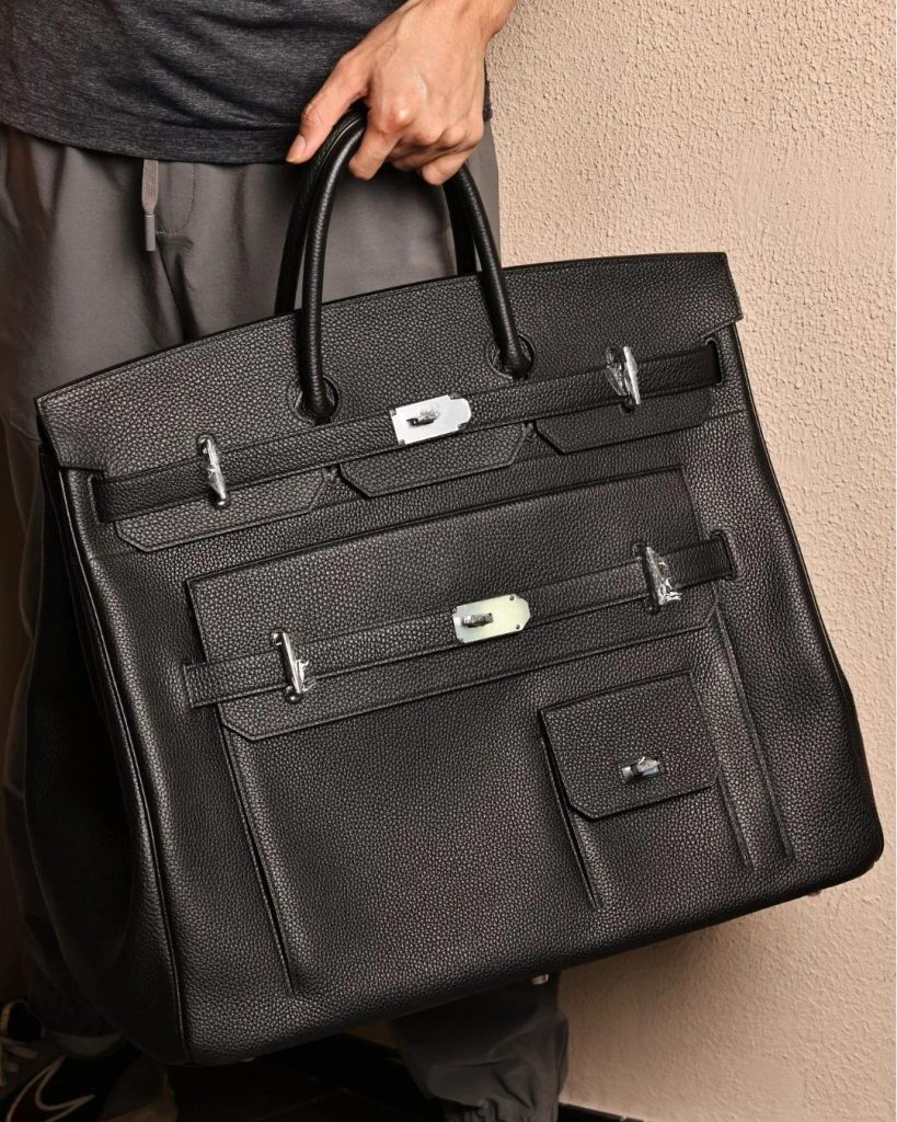 A person holding a black Hermès HAC bag with multiple pockets