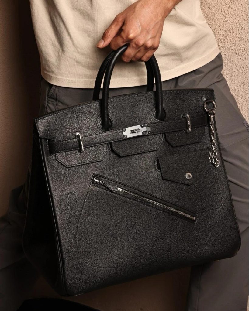 A person displaying a black Hermès HAC bag with edgy zipper details