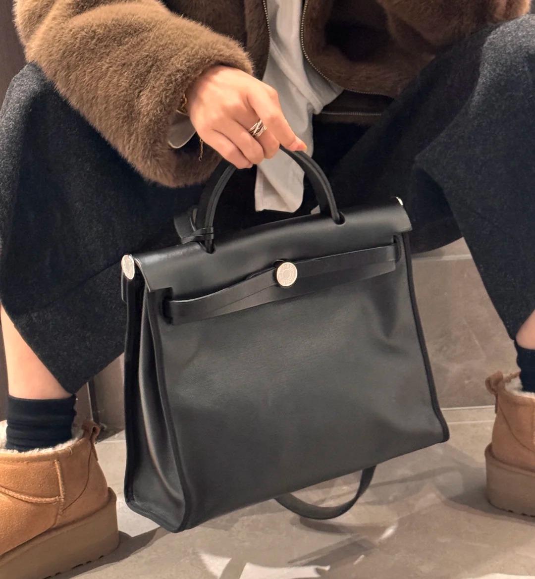 A person holding a black Herbag bag