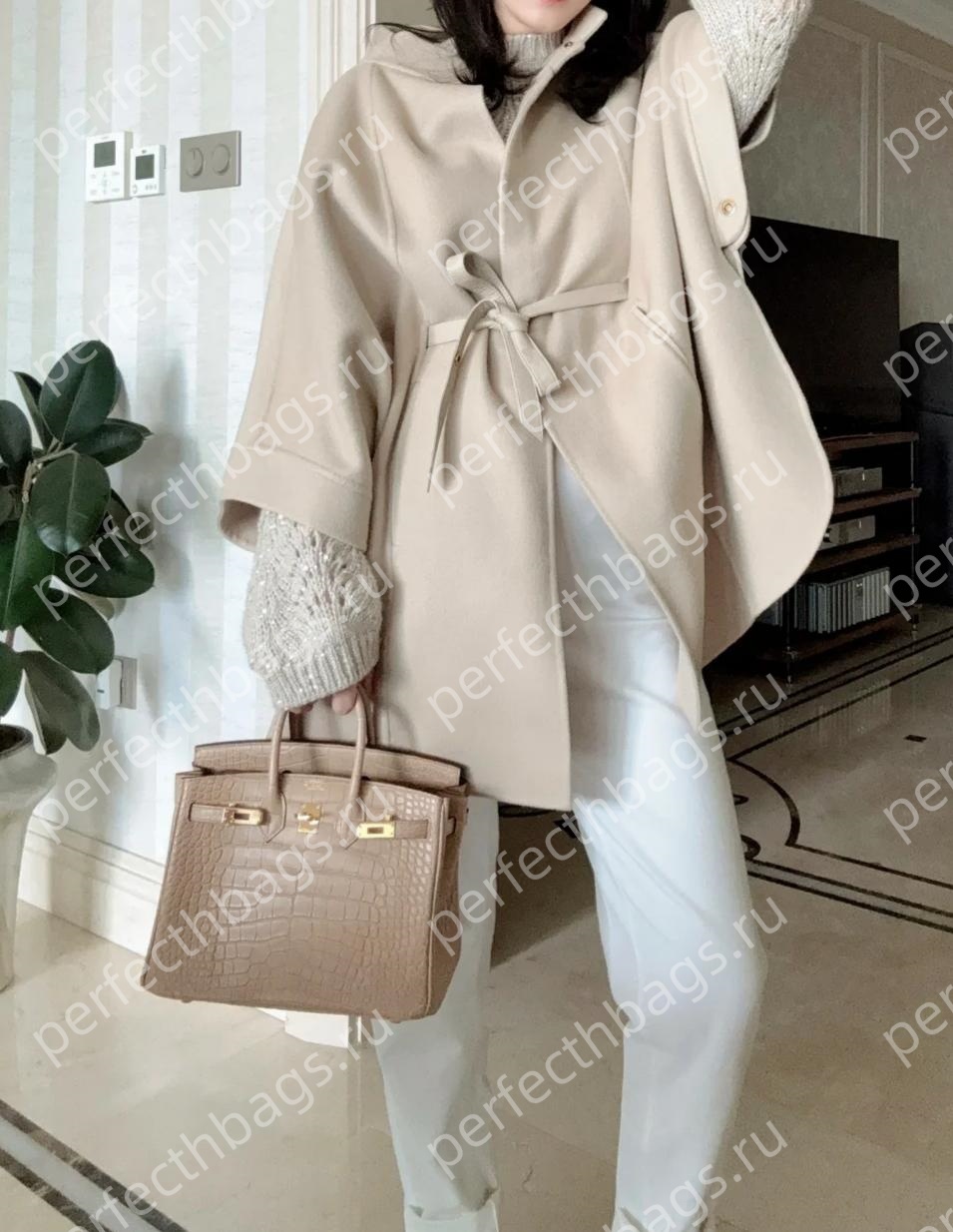Client wearing a beige crocodile Birkin bag with an elegant poncho, showing the perfect size and exotic scales.