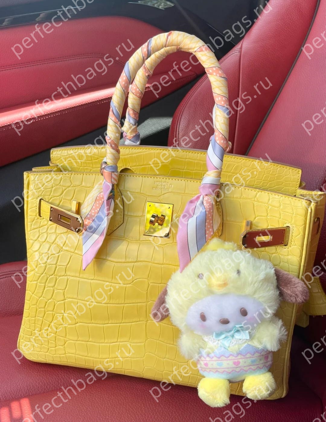 Bright yellow Hermes crocodile Birkin bag with twilly and charm inside a luxury car, exotic leather collectsion.