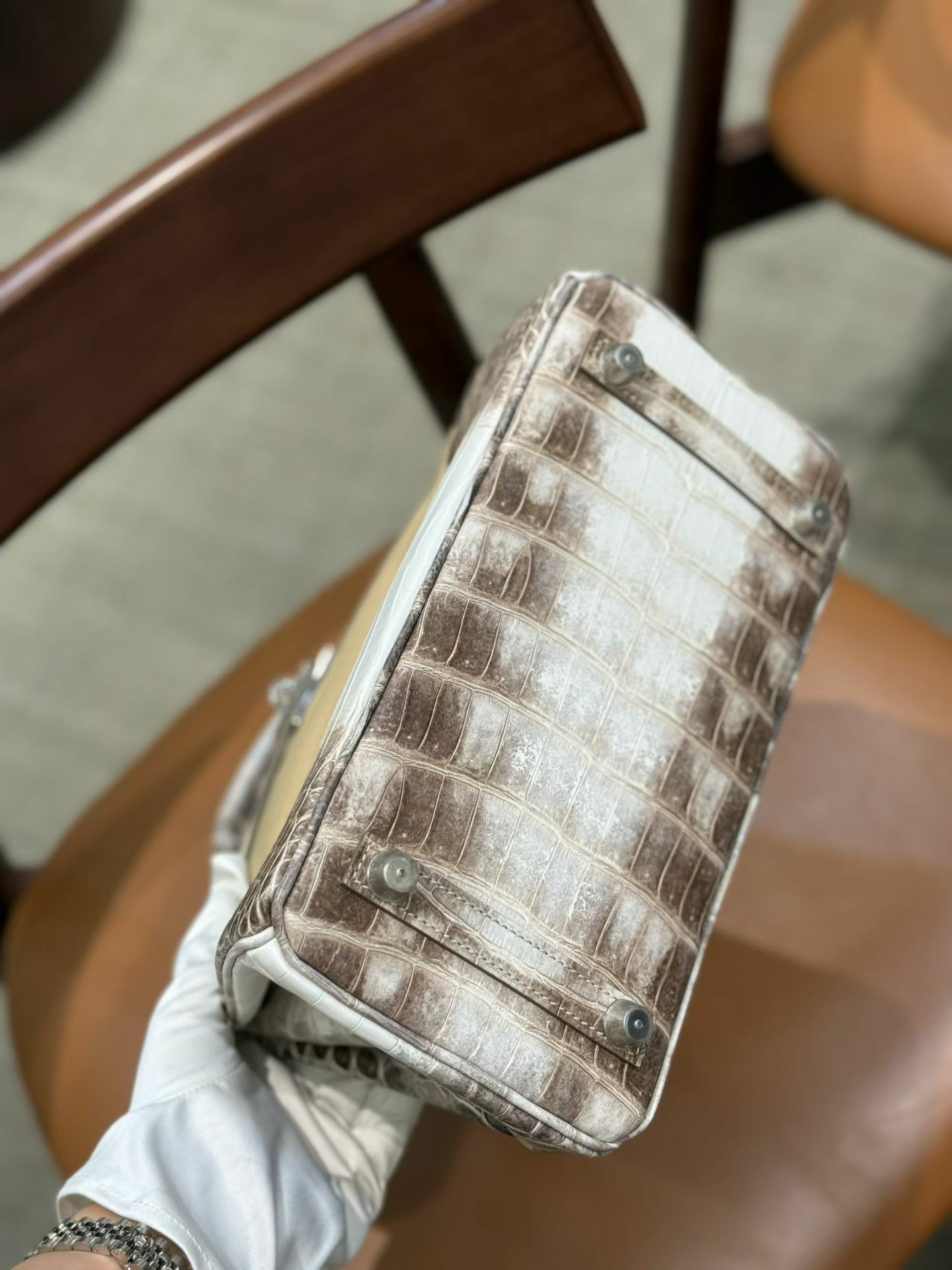 Gloved hand holding the base of a Himalayan Diamond Birkin 25